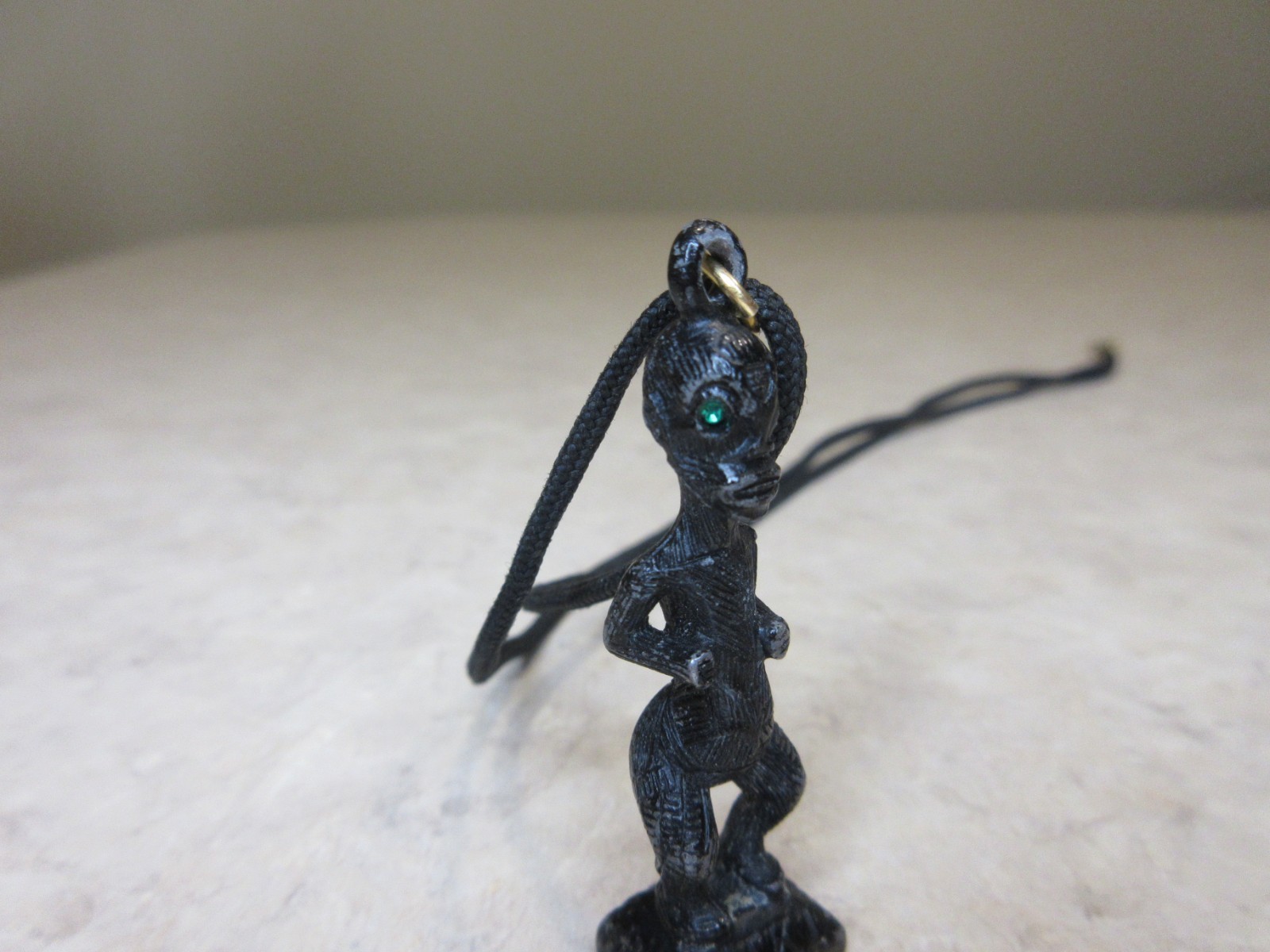 Vintage Metal Tiki Figurine Pendant From Polynesia. Black with green gem eye