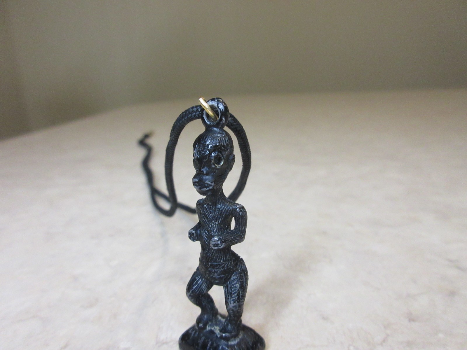 Vintage Metal Tiki Figurine Pendant From Polynesia. Black with green gem eye