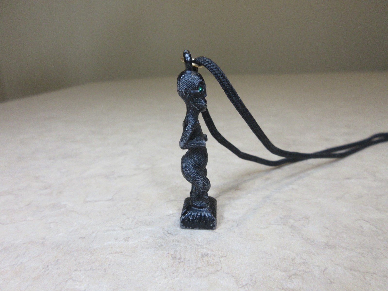 Vintage Metal Tiki Figurine Pendant From Polynesia. Black with green gem eye